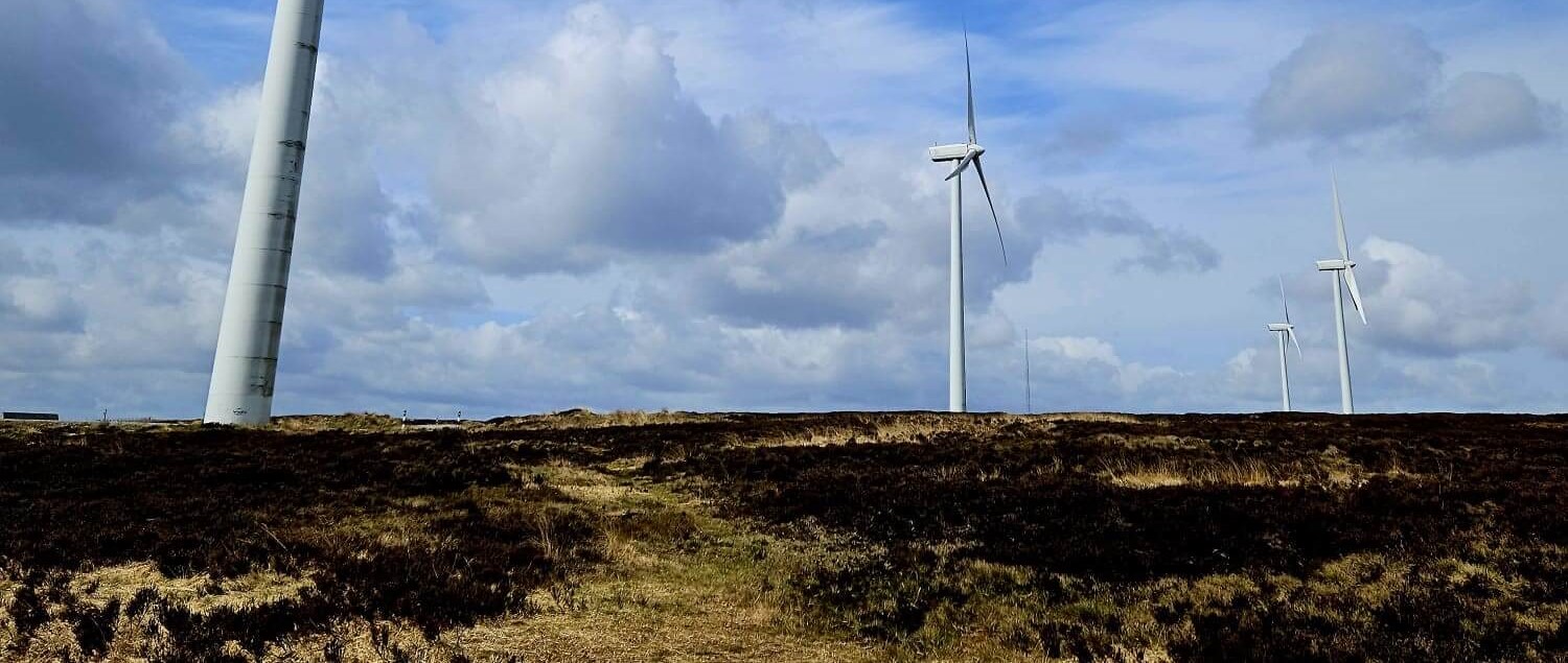 Ovenden Moor Wind Farm with four windmills set against a blue sky. 